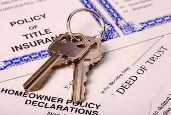 Picture of keys and a Title Insurance Policy to protect your ownership from disputes and claims